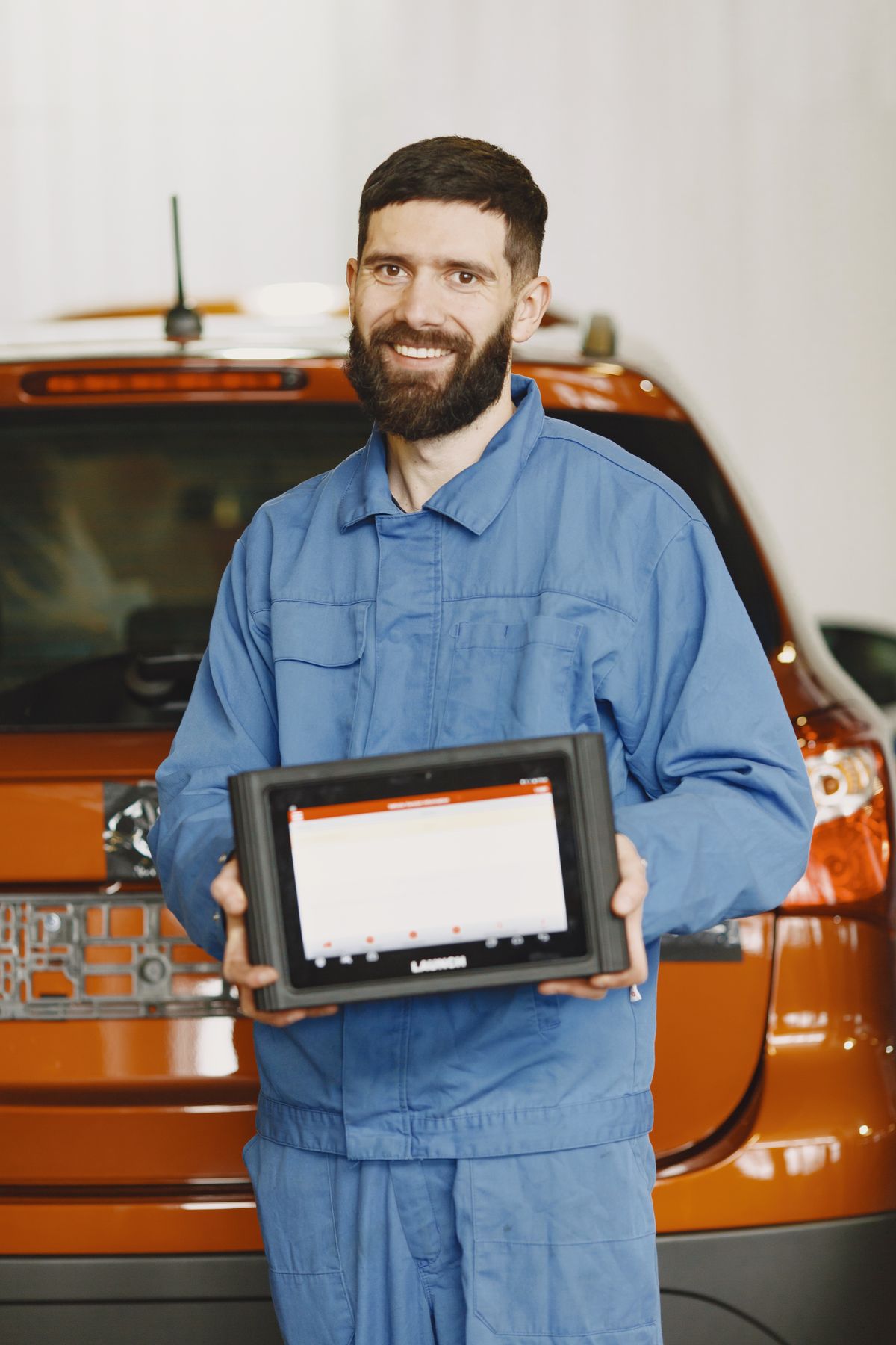 Mechaniker mit Diagnosegerät bei einer Fahrzeugprüfung